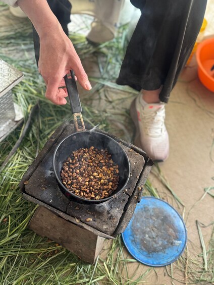 A person roasting coffee beans on an outdoor stove. 5