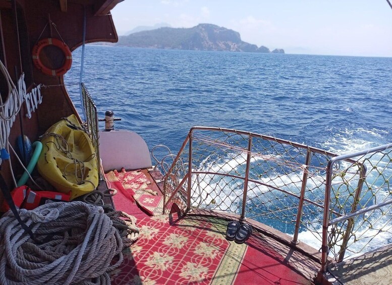 A boat's deck with ropes, a life preserver, and a view of the ocean with distant land. 5
