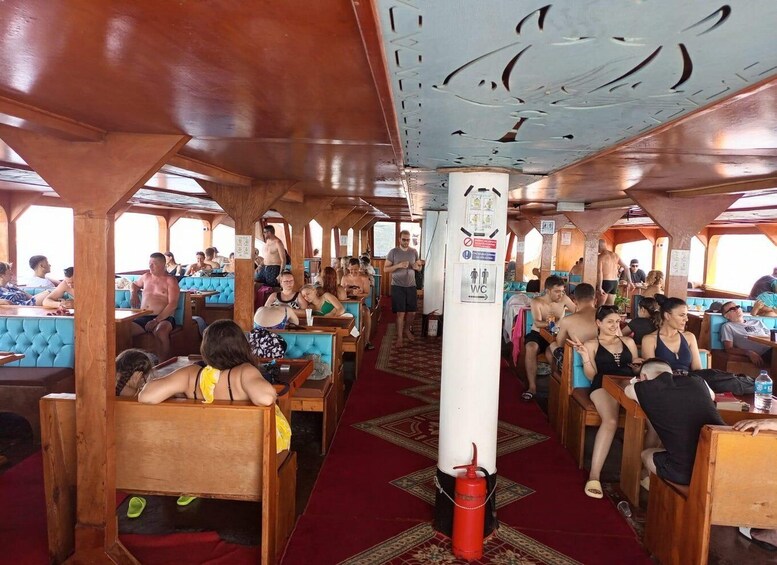 A cruise ship dining area with wooden tables and blue cushioned seating. 3