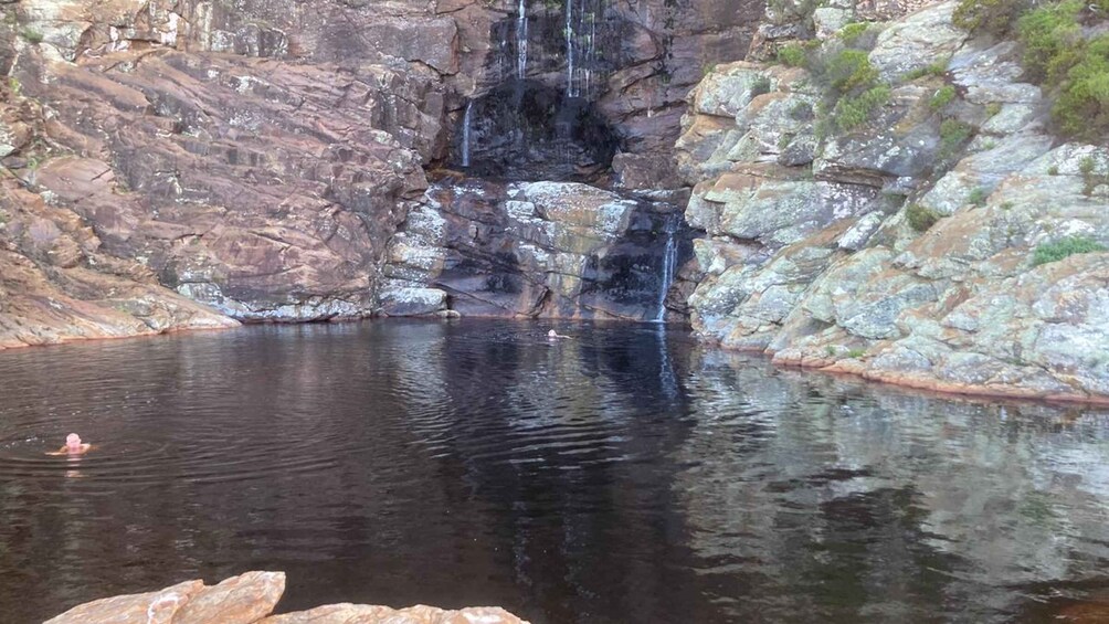 A natural pool with a waterfall, surrounded by rocky cliffs. 1