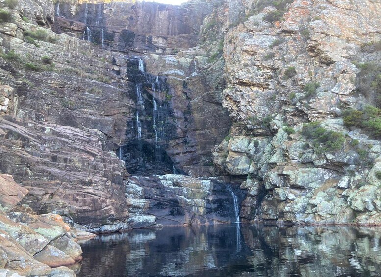 A waterfall cascading into a pool surrounded by rocky cliffs. 4