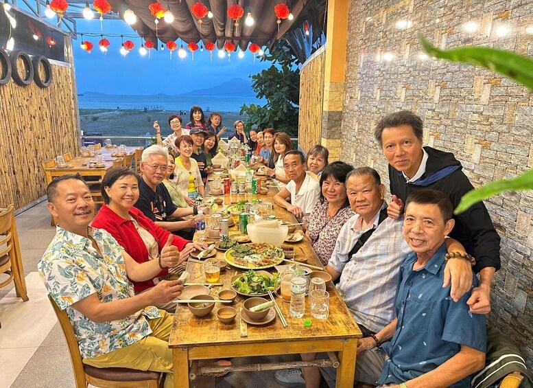 A group of people dining at an outdoor restaurant with a view of the sea. 2