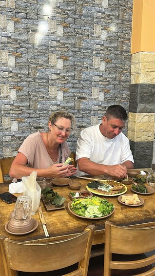 Two people dining at a table with a stone wall background. 5