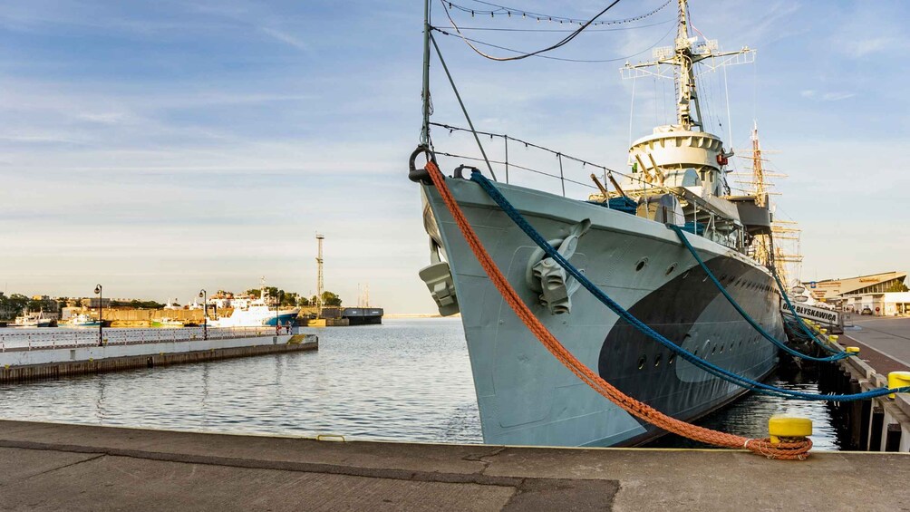 A large ship docked at a harbor with a clear sky and other boats in the background. 4