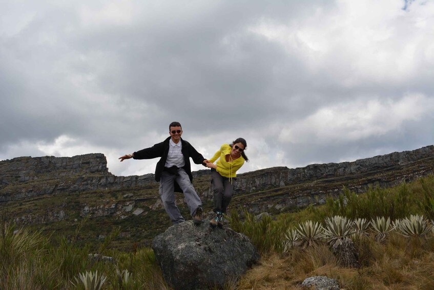 Two people standing on a rock with a mountainous landscape in the background. 2