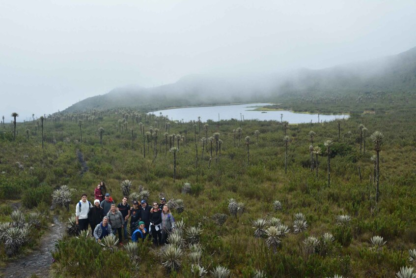 A group of people on a trail in a foggy, grassy landscape with a lake and mountains in the background. 4