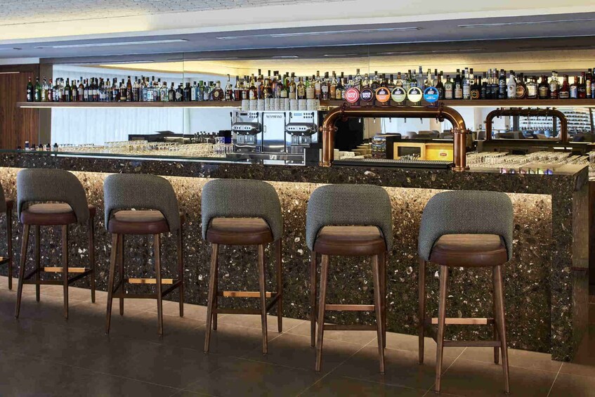A bar with a marble countertop, espresso machines, and a variety of liquor bottles. 2