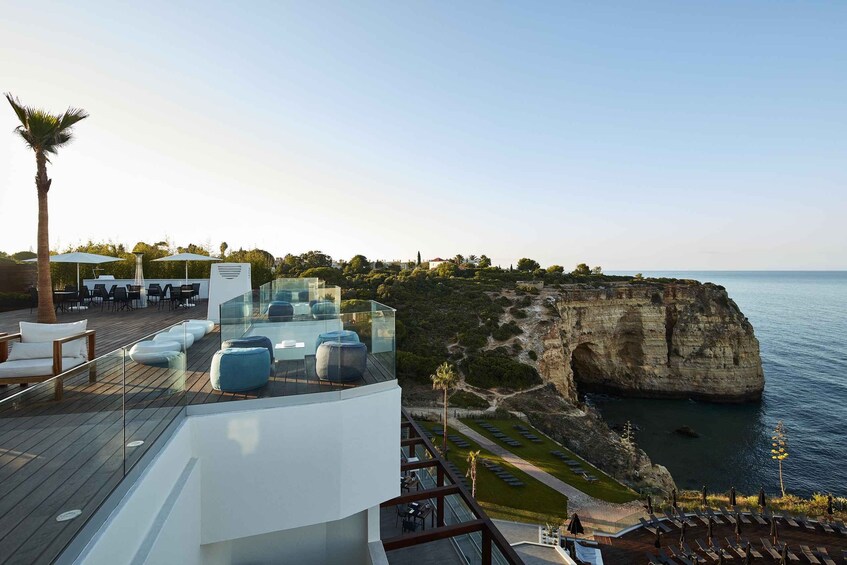 A rooftop terrace with outdoor seating overlooking a cliff and the sea. 3