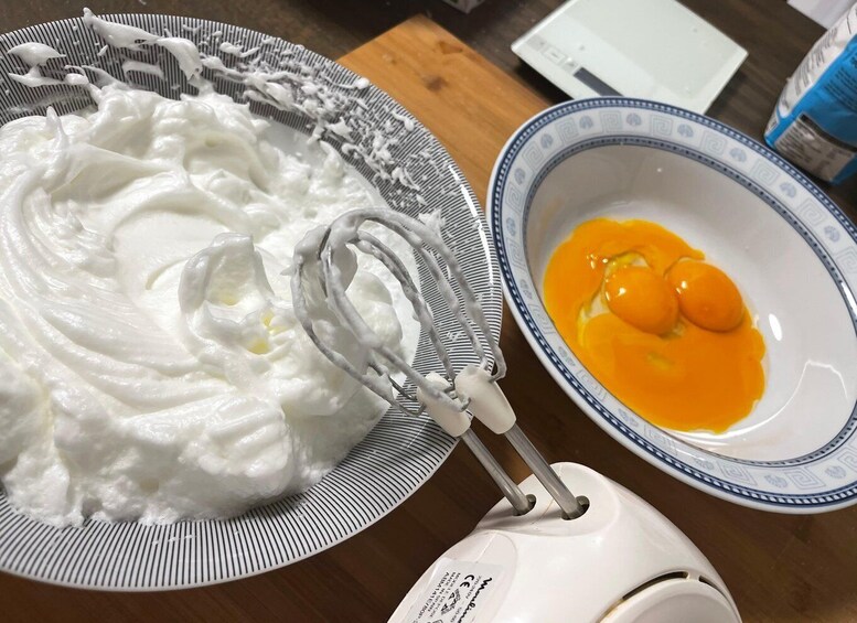 A bowl of whipped cream and a bowl of eggs on a kitchen counter. 2