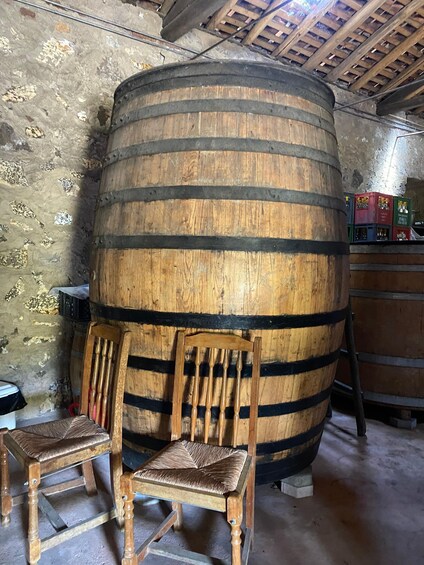 A large wooden barrel, a wooden chair, and crates in a rustic interior. 4