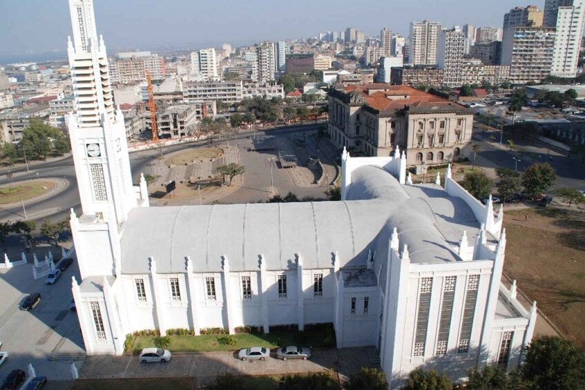 A large white church with a prominent tower and dome, surrounded by a cityscape with various buildings and a roundabout. 5
