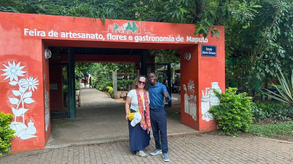 A red archway with 'Feira de artesanato, flores e gastronomia de Maputo' written on it, leading to a pathway. 4