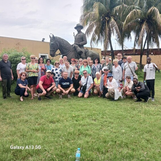 A group of people posing in front of a statue of a mounted figure and palm trees. 5