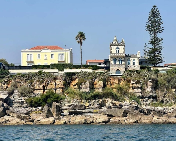 A coastal town with a yellow building, a tower, and rocky cliffs. 5