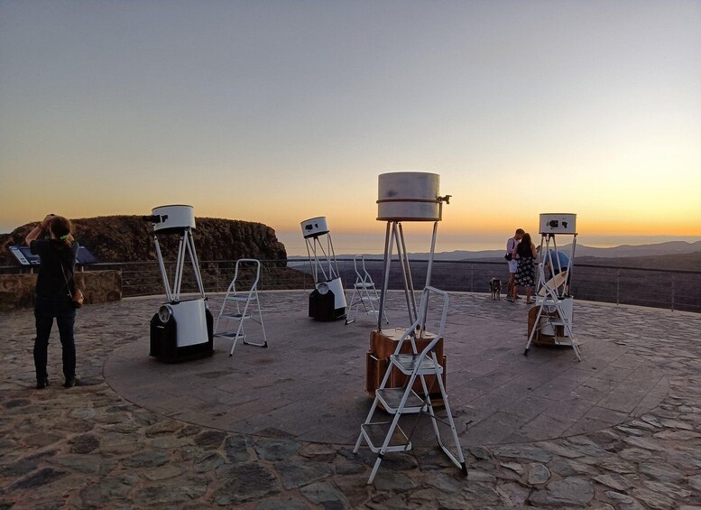 Telescopes on tripods on a stone platform with a sunset view. 1