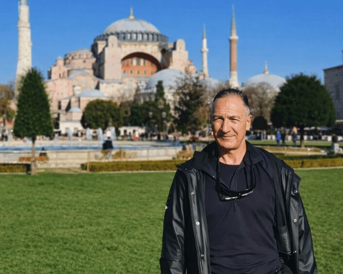 A person standing in a park with a historic building in the background. 4