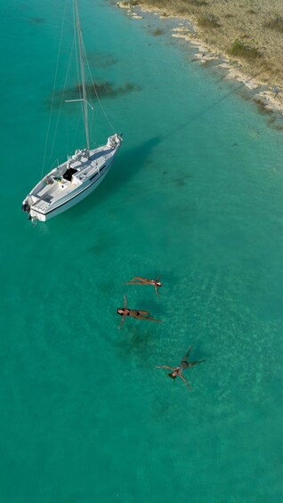 A sailboat anchored near a sandy beach with clear turquoise water. 5