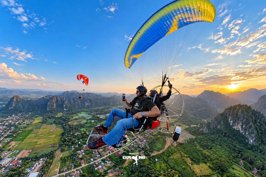A person paragliding over a mountainous landscape with a sunset in the background. 2