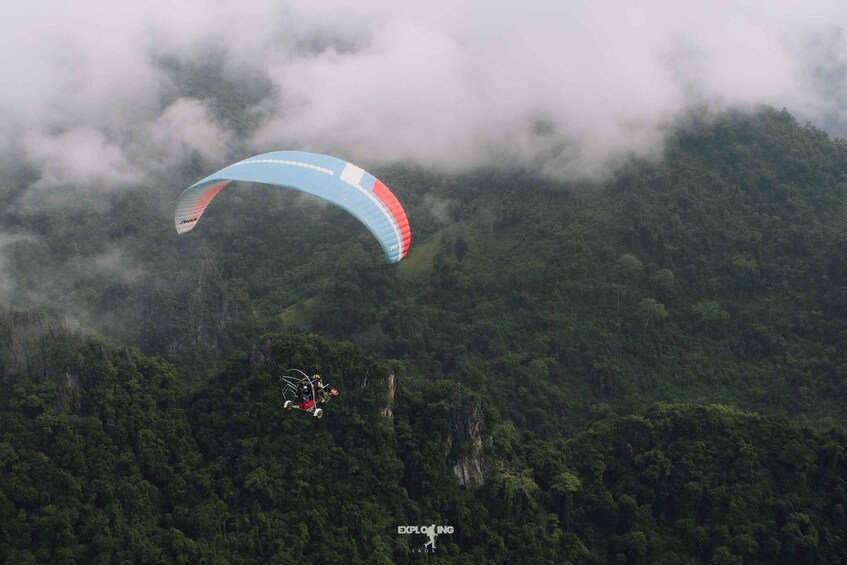 A paraglider flying over a forested mountain. 5