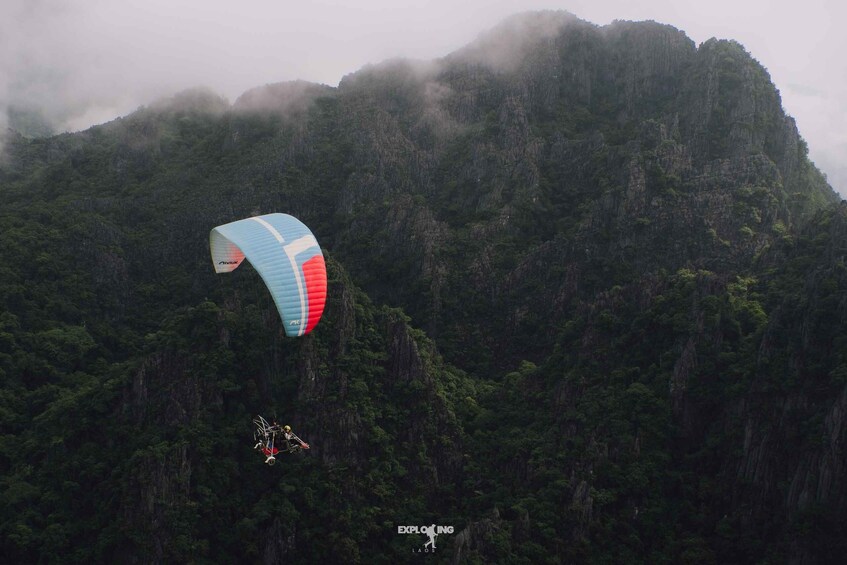 A paraglider descending towards a mountainous landscape. 4