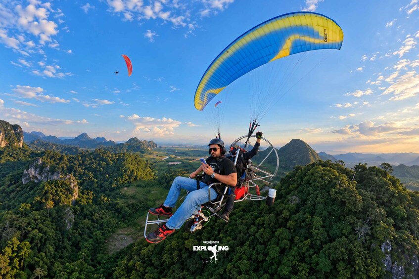 A person paragliding over a mountainous landscape with lush greenery and clear skies. 5