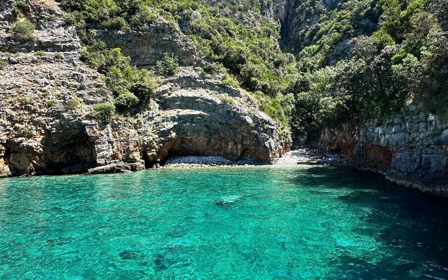A clear turquoise sea, rocky cliffs, and lush greenery. 5