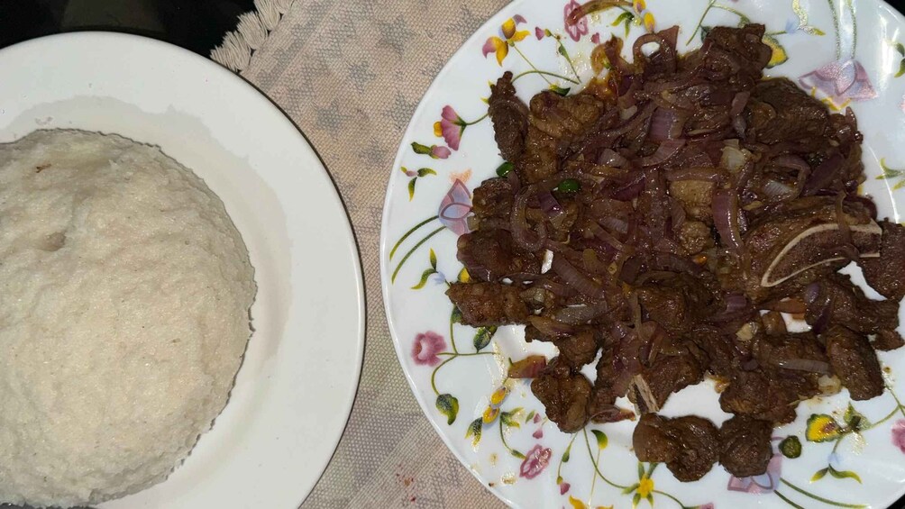 A plate of cooked meat with onions and a plate of flatbread. 2
