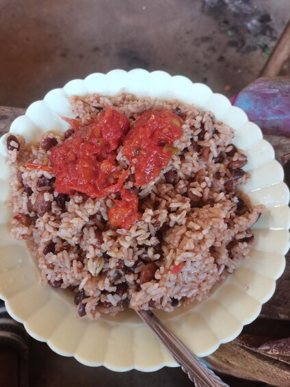 A plate of rice with beans and a red sauce. 4