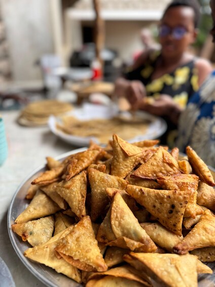 A plate of golden-brown samosas piled on a metal tray. 3