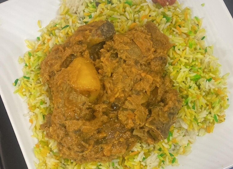 A plate of biryani with meat and potatoes. 5