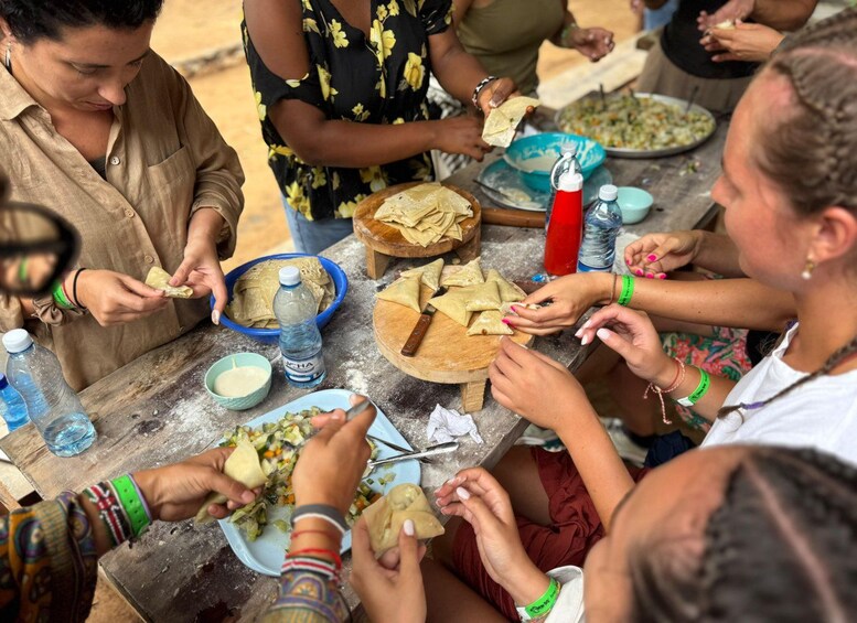 A group of people preparing food, with tortillas and a bowl of salad on a table. 1