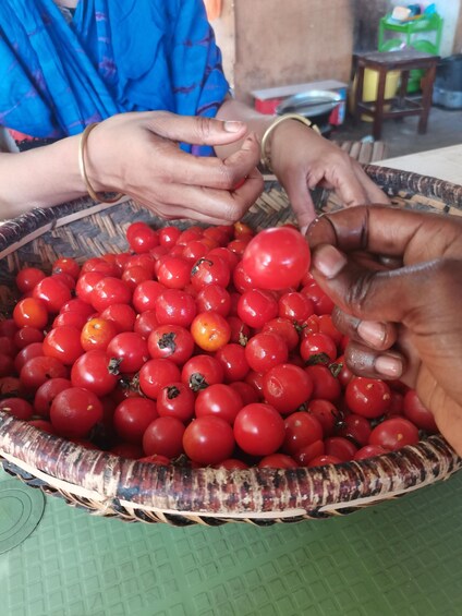 A person selecting red tomatoes from a woven basket. 1