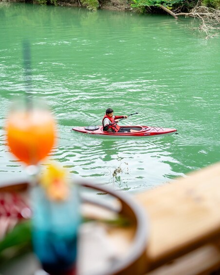 A person kayaking on a greenish river. 1