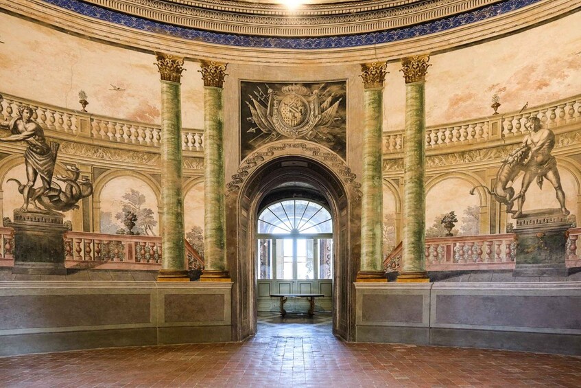 An ornate hall with classical statues, columns, and a central archway. 2