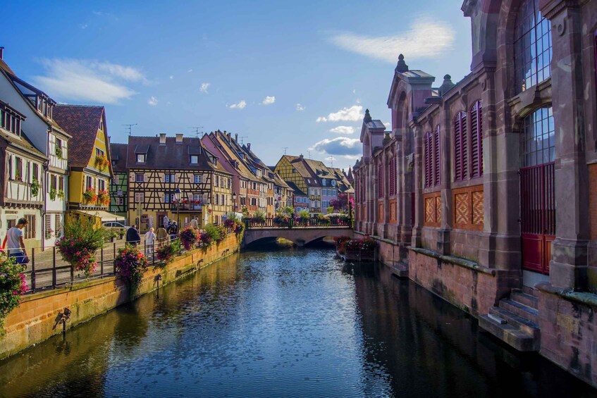 A canal with historic buildings on either side, a bridge, and people walking along the path. 5
