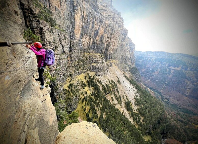 A person rappelling down a steep cliff with a vast canyon in the background. 1