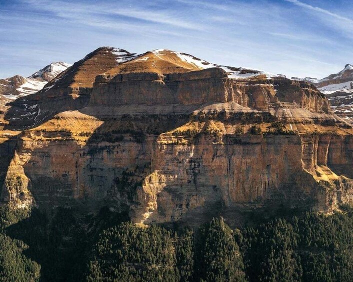 A mountain range with snow-capped peaks and dense forest at its base. 2