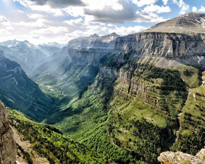 A mountainous landscape with a deep valley, steep cliffs, and dense forest. 4