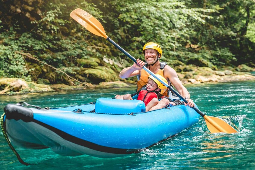 A person in a blue inflatable raft on a river, wearing a yellow helmet and life jacket, with a paddle in hand. 5
