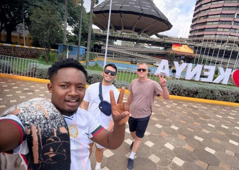 A group of people taking a selfie in front of a stadium with a large 'KENYA' sign. 1