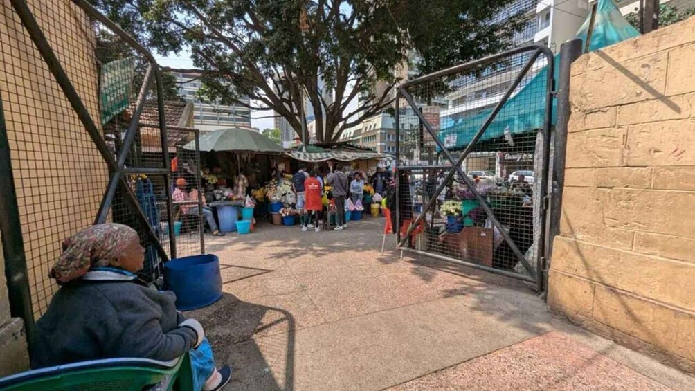 A market with vendors and customers, surrounded by trees and buildings. 5