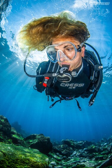 A diver underwater with a Cressi dive computer and regulator. 3