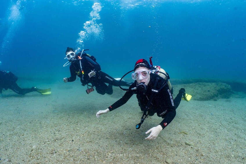 Two scuba divers underwater with fins and tanks. 2