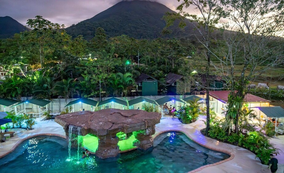 A pool with a rock feature and a mountain in the background. 2