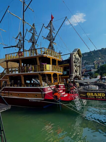 A wooden boat docked at a pier with a lifebuoy and a statue. 3