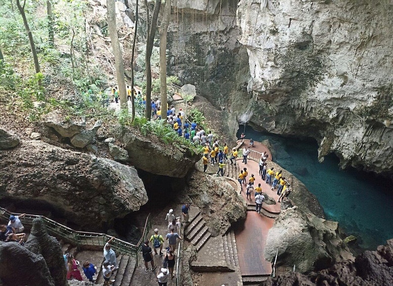 A group of people hiking in a rocky canyon with a clear blue pool at the bottom. 3