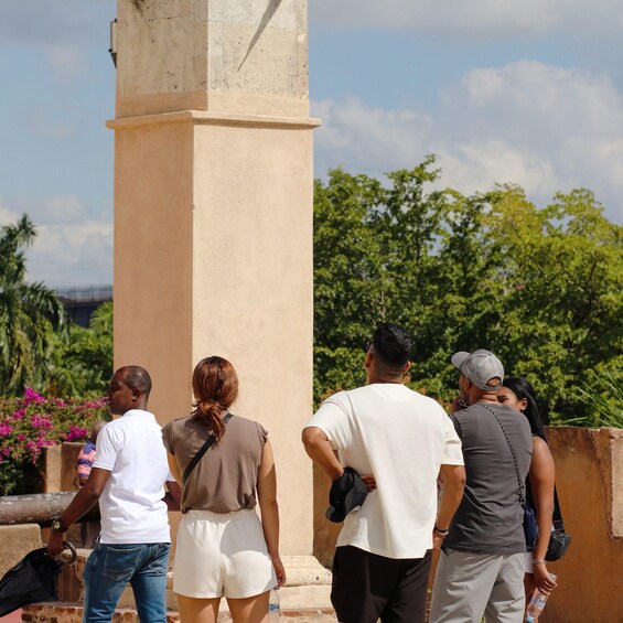 A group of people standing in front of a columned structure with greenery and flowers in the background. 4