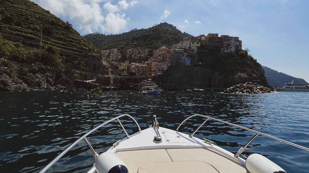 A boat on water with a coastal village on a cliff in the background. 3