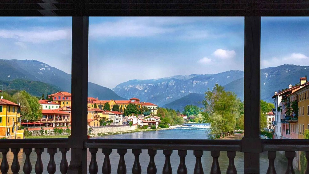 A river flowing through a town with colorful buildings and mountains in the background. 2