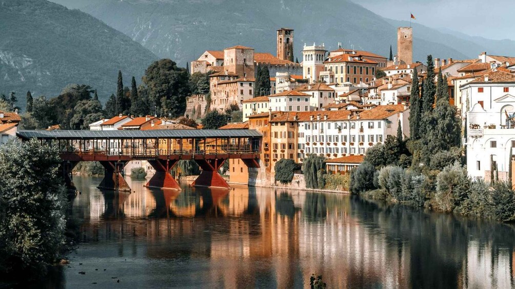 A river with a bridge, buildings, and mountains in the background. 3